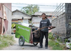 Sarito, a Plastic Bank collection community member, collects plastic waste using his collection cart around a residential area in Denpasar, Bali, Indonesia