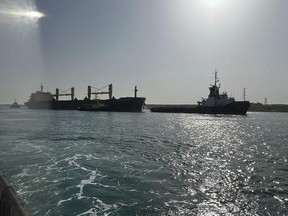 In this photo provided by The Suez Canal Authority in Egypt, the bulk carrier ship Xin Hai Tong 23, left, is towed after it ran aground at the southern mouth of the Suez Canal Thursday, May 25, 2023. The ship was being towed to another area by three tug boats after an "emergency malfunction," the authority said, that caused it to stop sailing, a rescue team of tugboats refloated it soon after. (Suez Canal Authority via AP)
