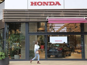 A woman walks past the logo of Honda Motor Co. in Tokyo on Oct. 19, 2021. Honda's profit for the fiscal year that ended in March dropped 1.7% as sales took a hit from a semiconductor shortage and restrictions in China related to the coronavirus pandemic. But the Japanese automaker said Thursday, May 11, 2023, that recovery was on the way, forecasting record sales and operating profitability for the current fiscal year.