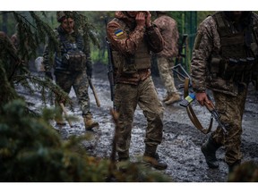 Ukrainian servicemen walk down a muddy road near the frontline town of Bakhmut, Donetsk region on April 30, 2023, amid the Russian invasion of Ukraine.  Photographer: Dimitar Dilkoff/AFP/Getty Images