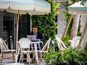 A customer works on a laptop computer in the outdoor dining area of Pura Vida restaurant on Rosemary Avenue in West Palm Beach, Fla.