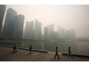 People look out towards the city skyline at Marina Bay as buildings in the central business district stand shrouded in smog in Singapore, on Thursday, Sept. 24, 2015. The haze from Indonesian forest fires pushed Singapore's air quality closer to the "hazardous" range, covering the city-state with a layer of smog as the government warned of a worsening condition over the public holiday.