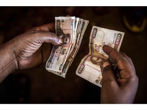 A market trader counts Kenyan shilling banknotes at a market stall in Mombasa, Kenya, on Thursday, Nov. 23, 2017. The country's Treasury has already cut this year's growth target to 5 percent from 5.9 percent as the protracted election furor damped investment and a drought curbed farm output.