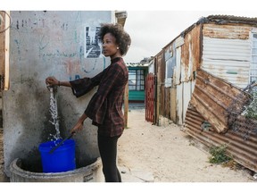 A resident fills a container with water from the communal tap in the Khayelitsha township, Cape Town. Photographer: Waldo Swiegers/Bloomberg