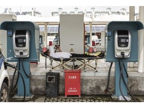 A taxi driver lies on a lounge chair as an electric vehicle charges at a charging station in Shenzhen, China, on Wednesday, Sept. 4, 2019. Shenzhen is young, hopeful and looks optimistically toward a future where it can help drive China's push to dominate the next century through an innovative economy that sidesteps political freedoms. The city also has the centralized control, relentless efficiency and advanced manufacturing that lie at the root of President Xi Jinping's concept of China's future greatness. Photographer: Qilai Shen/Bloomberg