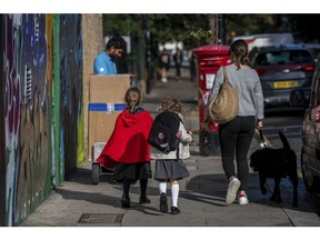 A pedestrian walks with two school children along Portobello Road in the Kensington district of London, U.K. on Friday, Sept. 27, 2019. From areas like Kensington, home to London department store Harrods but also housing projects with some of the capital's worst poverty, to places like Bishop Auckland with some of the country's highest unemployment, Brexit has redrawn tribal divisions and thrown up battlegrounds that would have been unthinkable just a few years ago. Photographer: Chris J. Ratcliffe/Bloomberg