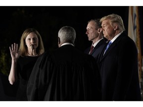 Justice Thomas, center, administers the judicial oath to Amy Coney Barrett, left, with husband Jesse Barrett, second right, and President Donald Trump, on the South Lawn of the White House, eight days before the 2020 presidential election.  Photographer: Ken Cedeno/CNP/Bloomberg