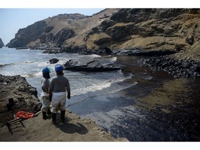 Workers observe an oil spill on Cavero beach in Callao, Peru, on Wednesday, Jan. 19, 2022. High ocean waves stemming from a massive volcanic eruption near Tonga caused an oil spill off the coast of Peru, closing beaches and halting fishing after the country's Navy failed to issue a tsunami warning.