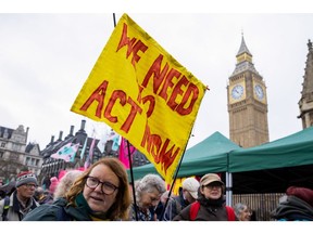 A protester outside the Houses of Parliament with a banner that reads "We Need To Act Now" during the first day of the "The Big One" protest organised by Extinction Rebellion in London, UK, on Friday, April 21, 2023. The UK arm of environmental activist group Extinction Rebellion said it plans to step away from attention-grabbing tactics that have caused widespread public disruptions and instead focus on building broader support to help combat rising carbon emissions. Photographer: Betty Laura Zapata/Bloomberg