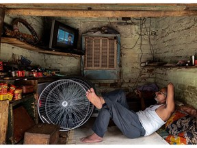 A vendor watches television while resting inside a bicycle repair shop in New Delhi, India, on Friday, May 19, 2023. The extreme heat that baked parts of Southeast Asia last month was largely driven by human-induced climate change, according to analysis from a team of scientists. Photographer: Anindito Mukherjee/Bloomberg