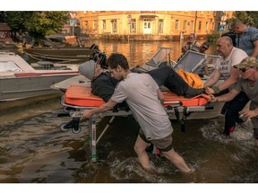 KHERSON, UKRAINE - JUNE 09: Volunteers and others push a stretcher carrying an elderly person who was evacuated from a flooded area on June 9, 2023 in Kherson, Ukraine. Early Tuesday, the Kakhovka dam and hydroelectric power plant, which sit on the Dnipro river in the southern Kherson region, were destroyed, forcing downstream communities to evacuate due to the risk of flooding. The cause of the dam's collapse is not yet confirmed, with Russia and Ukraine accusing each other of its destruction. The Dnipro river has served as a frontline between the warring armies following Russia's retreat from Kherson and surrounding areas last autumn. The dam and plant had been under the control of Russia, which occupies a swath of land south and southeast of the river.