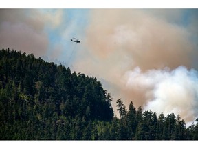 A helicopter waterbomber flies above the Cameron Bluffs wildfire near Port Alberni, British Columbia, Canada, on Monday, June 5, 2023. Canada is on track to see its worst-ever wildfire season in recorded history if the rate of land burned continues at the same pace.