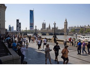 Visitors pass along the Thames walkway against a backdrop of the Palace of Westminster in London, UK, on Saturday, June 10, 2023. Soaring temperatures caused by a blast of hot air led the UK to post fresh health warnings through the weekend. Photographer: Chris Ratcliffe/Bloomberg