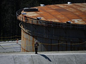 A worker stands on a concrete berm at the Trans Mountain Pipeline expansion project at the Burnaby Terminal tank farm in Burnaby, B.C., in March.