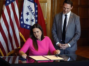 FILE - Arkansas Gov. Sarah Huckabee Sanders signs a bill requiring age verification before creating a new social media account as Sen. Tyler Dees, R-Siloam Springs, looks on during a signing ceremony, Wednesday, April 12, 2023, at the state Capitol in Little Rock, Ark. , NetChoice, a tech industry trade group, is suing Arkansas over its law requiring parental permission for minors to create new social media accounts.