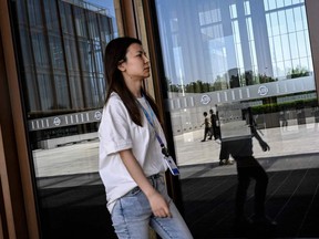 A woman walks past a gate at the headquarters of the Asian Infrastructure Investment Bank (AIIB) in Beijing on June 15, 2023.