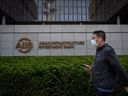 A man walks past the logo of the Asian Infrastructure Investment Bank (AIIB) at its headquarters in Beijing.