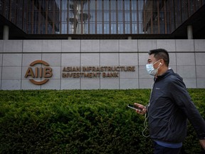A man walks past the logo of the Asian Infrastructure Investment Bank (AIIB) at the headquarters in Beijing.