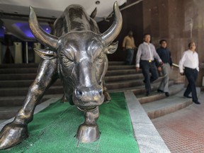 Des personnes passent devant la statue de bronze d'un taureau à l'entrée du bâtiment de la Bourse de Bombay, à Mumbai, en Inde. Les actions indiennes sont sous-estimées, selon les analystes.