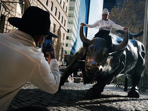 A man sits on the Wall street bull near the New York Stock Exchange in New York City.