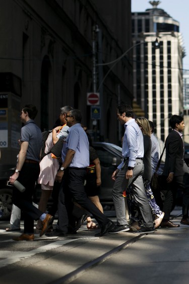 Commuters cross a street in Toronto's financial district in July, 2019.
