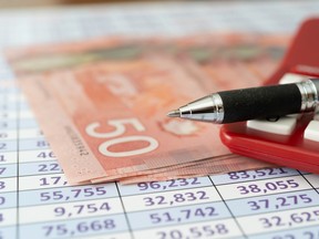 Canadian banknotes on a spreadsheet with calculator and pen