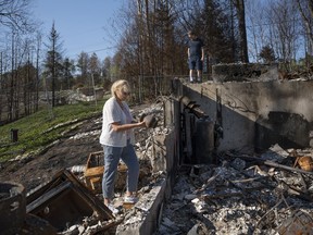 Maureen McGee discovers the urn containing her dogs' ashes while she and her husband Paul search for belongings in the ruins of their family's home after it was destroyed in a wildfire earlier this month in the suburban community of Hammonds Plains, N.S. outside of Halifax on Thursday, June 22, 2023.