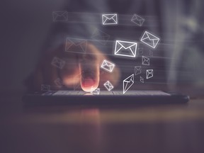 Man's finger touching a phone surrounded by email icons