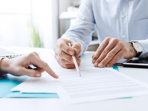 Business people negotiating a contract, pointing to a document