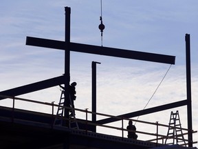 Workers guide and secure steel beams on top of a building during construction
