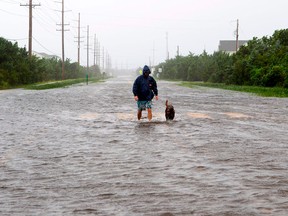 A man walks with his dog on a flooded road in Salvo, North Carolina after a hurricane hit.