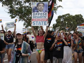 Parade participants carrying signs opposing Gov. Ron DeSantis during the St. Pete Pride Parade along Bayshore Drive on Saturday, June 24, 2023, in St. Petersburg, Fla.
