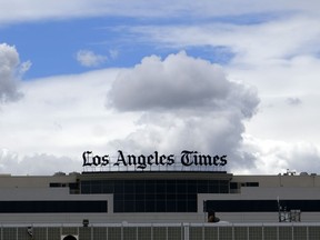 FILE - The Los Angeles Times building is seen behind a fence behind the Los Angeles International Airport, Friday, April 10, 2020. The Los Angeles Times on Wednesday, June 7, 2023, announced plans to cut 74 jobs due to economic challenges as the newspaper strives to transform itself into a digital media organization.