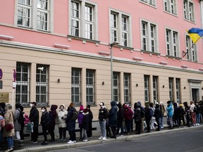 FILE -People from Ukraine, most of them refugees fleeing the war, wait in front of the consular department of the Ukrainian embassy in Berlin, Germany, on April 1, 2022. Large numbers of refugees from Ukraine fueled a 1.3% rise in the German population last year, helping push up the number of inhabitants in the European Union's most populous country to more than 84.4 million, official statistics showed Tuesday, June 20, 2023.