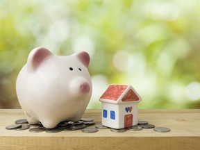 A piggy bank, money, and a small house to illustrate saving for a home