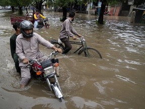 Motorcyclists drive through a flooded road caused by heavy rainfall, in Lahore, Pakistan, Monday, June 26, 2023.