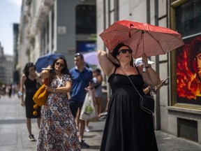 FILE - A woman holds an umbrella to shelter from the sun during a hot sunny day in Madrid, Spain, on July 18, 2022. Spain registered its hottest spring on record this year, and its second driest ever, the state meteorological agency said Wednesday, June 7, 2023.
