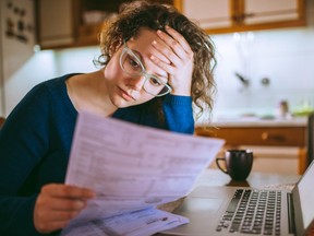 Young woman reading a paper bill, looking stressed.