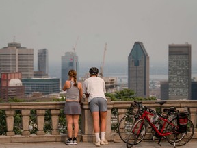 People look out at the city of Montreal shrouded in smoke from wildfires burning north of Quebec.