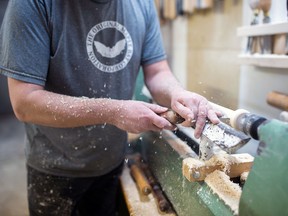 An employee hand shapes a custom maple wood bat during production at the Sam Bat manufacturing facility in Ottawa