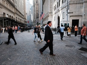 People walk along Wall Street by the New York Stock Exchange in New York City.