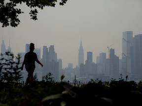 A pedestrian walking along the waterfront in West New York, New Jersey, on June 8, 2023, as smoke haze from Canadian wildfires blankets the area.