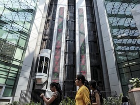 Employees walk past electronic ticker boards that indicate the latest stock figures inside the atrium at the National Stock Exchange in Mumbai, India.