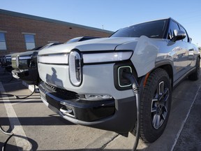 File - A 2023 R1T pickup truck is charged in a bay at a Rivian delivery and service center Wednesday, Feb. 8, 2023, in Denver. Electric vehicle maker Rivian says it will follow General Motors and Ford and join Tesla's charging network next year. The startup truck, SUV and delivery van maker says Tuesday, June 20, that like GM and Ford, it will include ports with Tesla's connector on future Rivian vehicles starting in 2025.