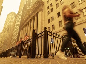 A pedestrian walks past the smoke and haze shrouded New York Stock Exchange building in New York City Wednesday, June 7, 2023. Intense Canadian wildfires are blanketing the northeastern U.S. in a haze, turning the air acrid and the sky yellowish gray.