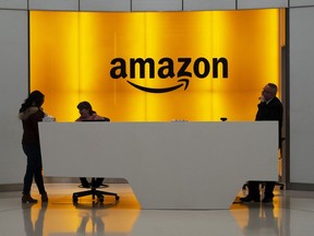 FILE - In this Feb. 14, 2019, file photo people stand in the lobby for Amazon offices in New York. Amazon is kicking off its annual security-focused cloud computing conference on Tuesday amid a slowdown in its profitable cloud business Amazon Web Services, or AWS.