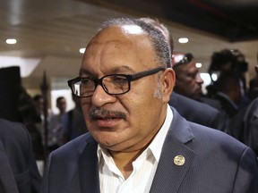 FILE - Papua New Guinea's Prime Minister Peter O'Neill is chased by reporters after reading his statement at the end of the APEC 2018 summit at Port Moresby, Papua New Guinea, Nov. 18, 2018. O'Neill said police charged him on Monday, June 12, 2023, with providing false evidence in an inquiry into a multi-million-dollar government loss on an investment deal.