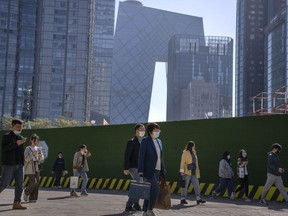FILE - Commuters walk along a path in the central business district during the morning rush hour in Beijing, on April 18, 2023. Foreign companies are shifting investments and their Asian headquarters out of China as confidence plunges following the expansion of an anti-spying law and other challenges, a business group said Wednesday, June 21, 2023.