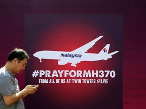 FILE - A man walks past a board reading "Pray for MH370" for passengers aboard a missing Malaysia Airlines plane, in Kuala Lumpur, Malaysia, on March 15, 2014. Malaysia's government on Thursday, June 8, 2023, condemned a Singapore-born stand-up comedian who mocked Malaysia and made fun of the 2014 disappearance of Malaysia Airlines Flight MH370 during a skit in the United States.