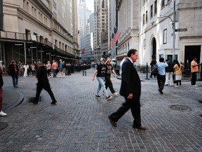 People walk along Wall Street by the New York Stock Exchange. Wall Street chiefs have been among the loudest in pushing for a return to the office five days a week.